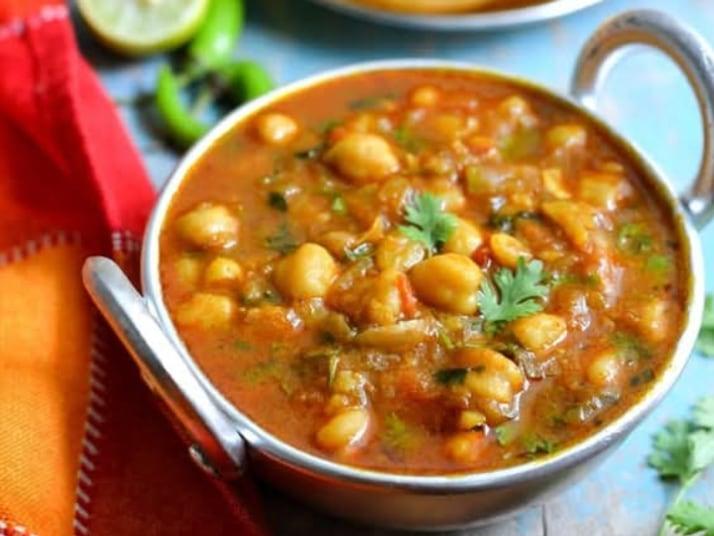 A karahi of chole, the chickpeas in a dark masala with fresh coriander