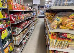 An aisle inside the shop, shelves stacked with Indian snacks, spice packets and bags of bread